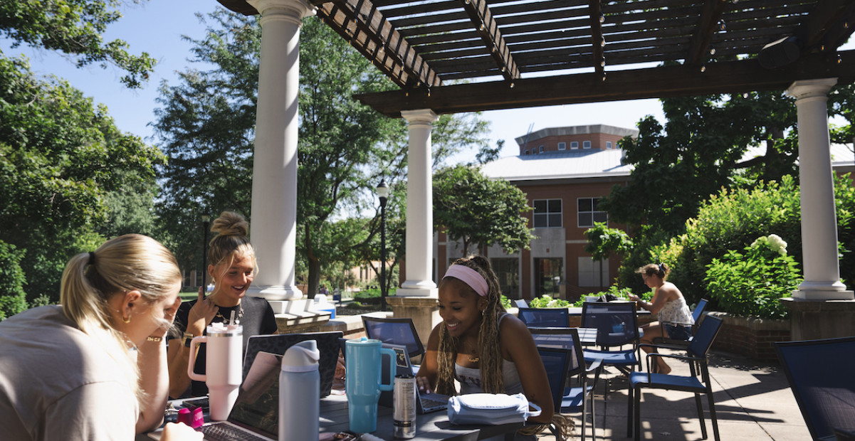 Students sitting on the Baxter patio at a table working on homework