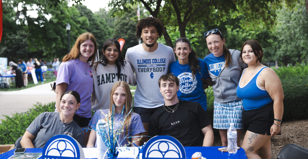 Group of Illinois College students sitting at a table outdoors and smiling