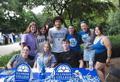 Group of Illinois College students sitting at a table outdoors and smiling