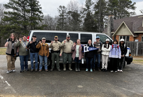 Students posing in front of shuttle van at alternative spring break trip