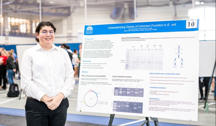 Student poses with his poster presentation