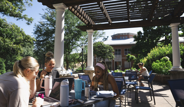 Students sitting on the Baxter patio at a table working on homework